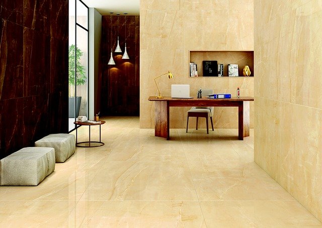 Modern office with beige marble floors, wooden desk, and books on shelves. Soft lighting, neutral tones, and sleek decor create a calm vibe.