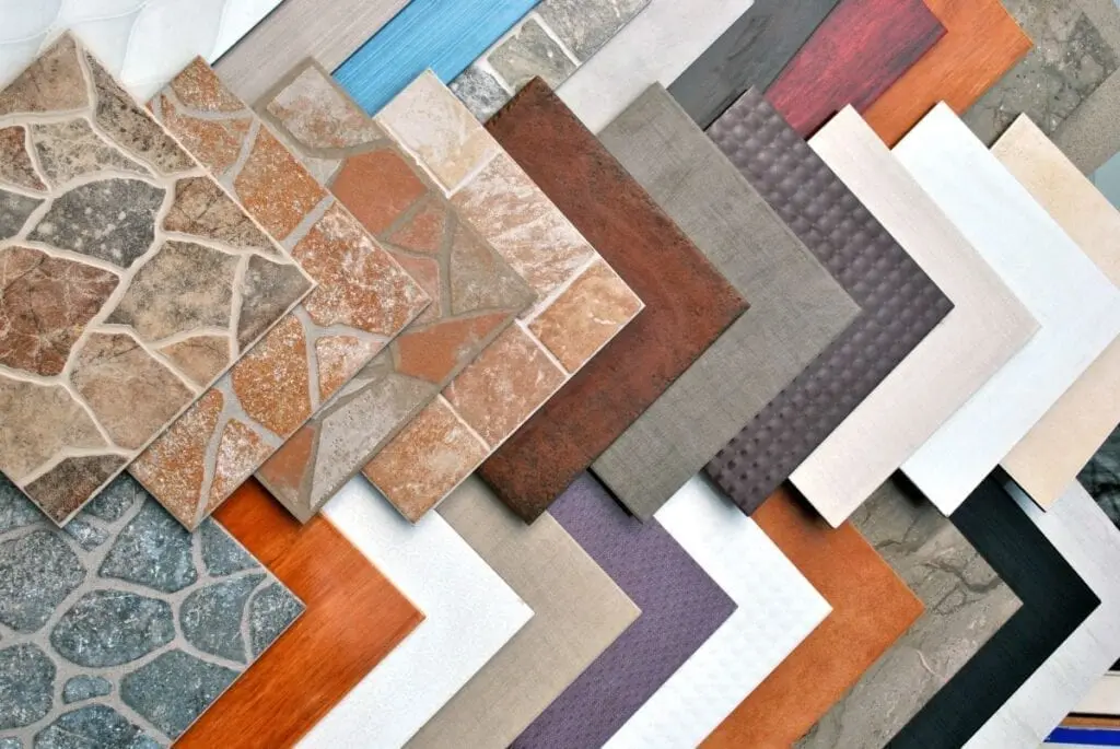 Assortment of square ceramic tiles in various colors and patterns, including stone, wood, and solid colors.
