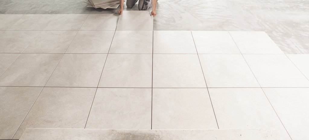 Light gray square tiles are laid out in a grid pattern on a floor.